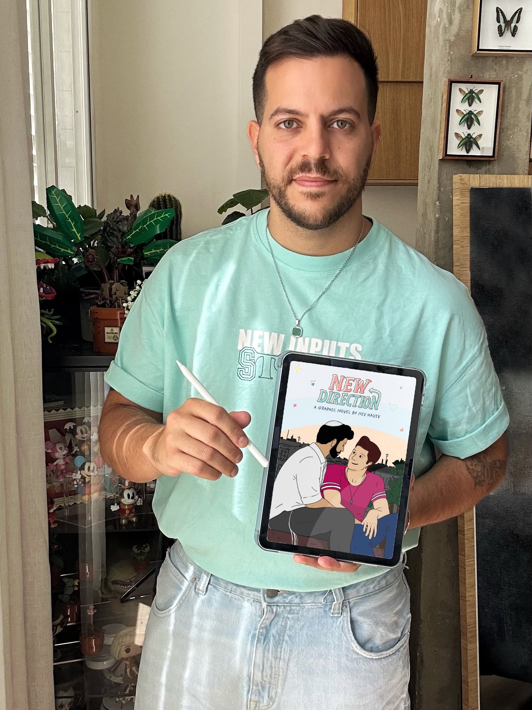 ניב מחזיק אייפד עם כריכת הרומן הגרפי כיוון חדש